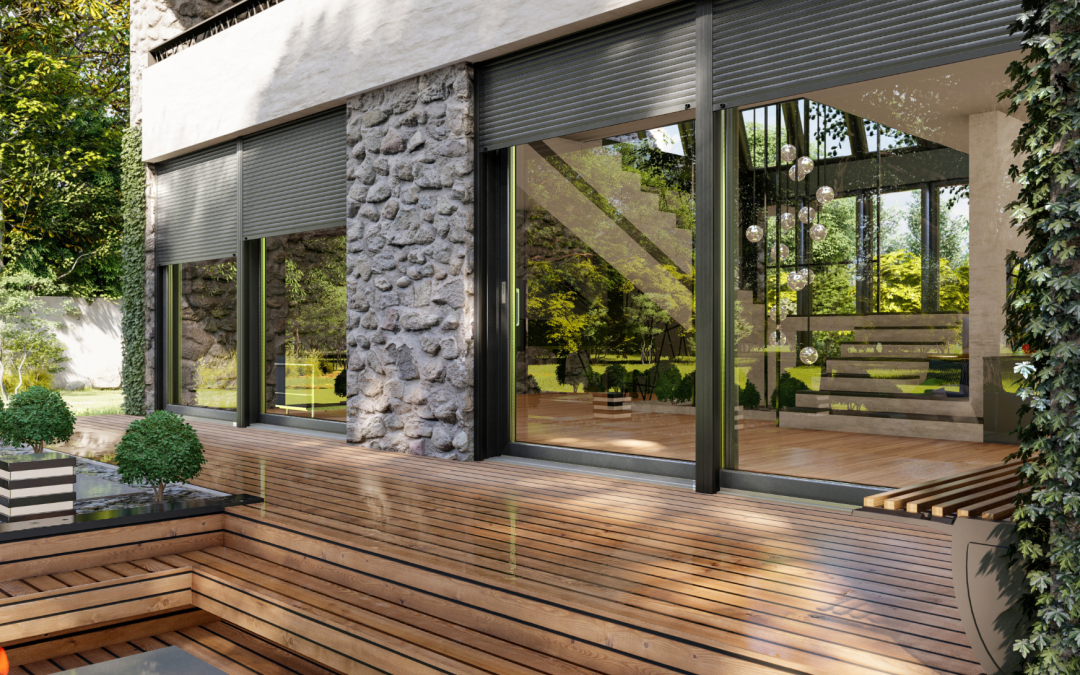 Modern house exterior with a stone wall, large glass sliding doors, and a multi-tiered wooden deck overlooking greenery.
